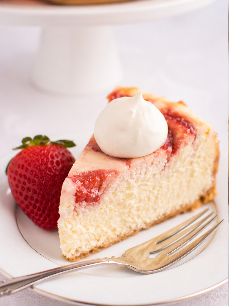 White chocolate strawberry cheesecake with strawberry swirl and white chocolate-covered strawberries
