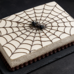 Black cocoa sheet cake with mostly white buttercream spiderweb design and candy spiders
