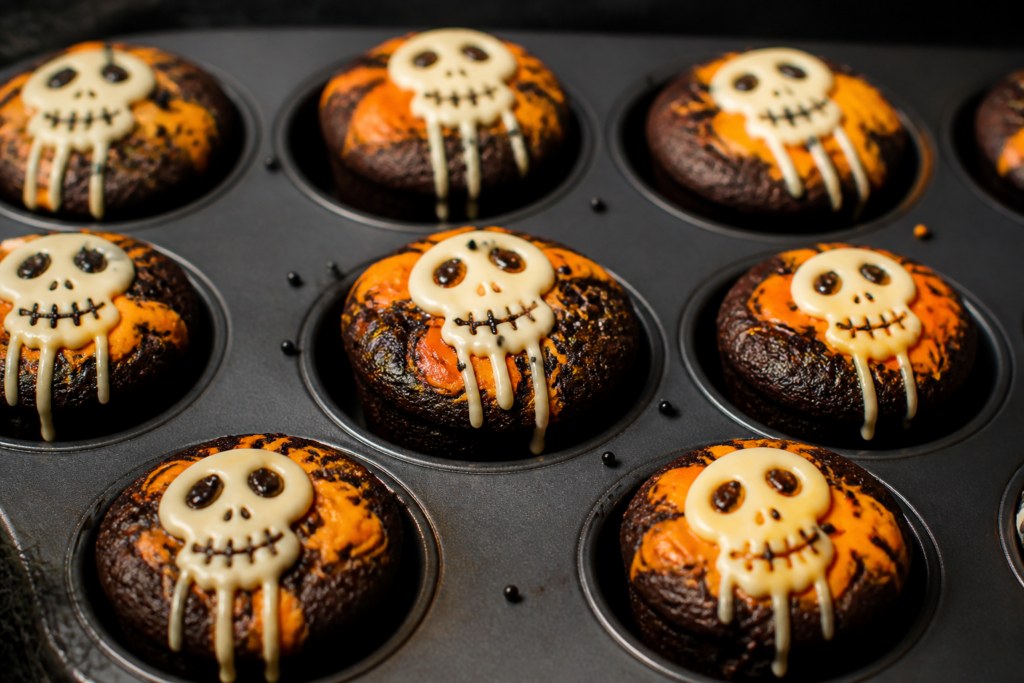 Halloween black cocoa brownie bites with orange cream cheese swirl and a simple white chocolate skull drizzle