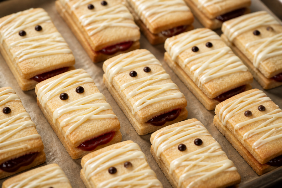 Finished mummy raspberry jam shortbread sandwich cookies with white chocolate bandage drizzle and dark chocolate eyes