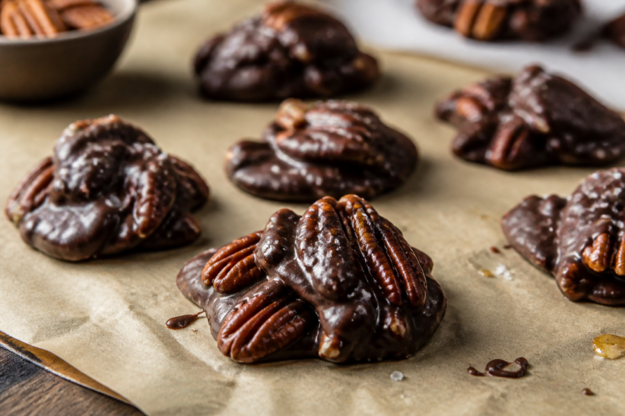 Salted maple pecan dark chocolate clusters on parchment with flaky sea salt