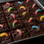 Sour gummy worm chocolate dirt fudge squares with cocoa cookie soil and neon gummy worm tops