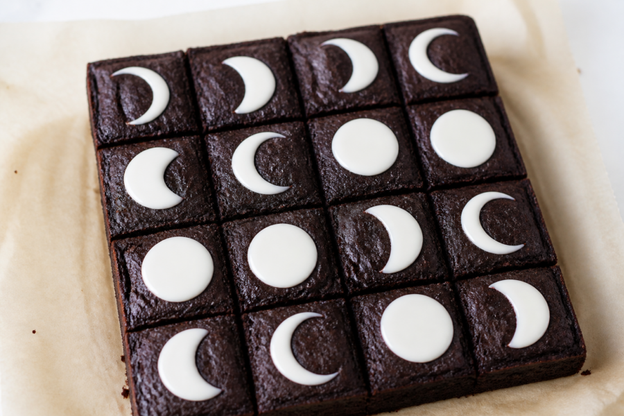 Finished 8x8 Halloween black cocoa moon phase brownies with vanilla glaze in a clean grid of white crescents