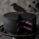 Finished gothic raven blackberry layer cake with black cocoa frosting and tempered chocolate raven silhouette