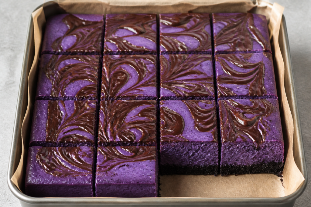 Black magic ube Oreo cheesecake bars with a glossy dark-chocolate swirl in a square pan