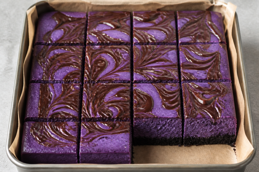 Black magic ube Oreo cheesecake bars with a glossy dark-chocolate swirl in a square pan