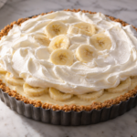 No-bake banana pudding cheesecake tart with vanilla wafer crust, topped with a thin vanilla whipped swirl and banana slices