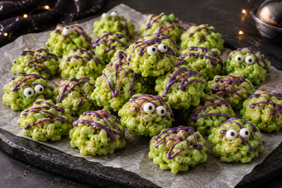 Alien slime crispy rice treats on parchment with neon lime green bites and purple chocolate drizzle