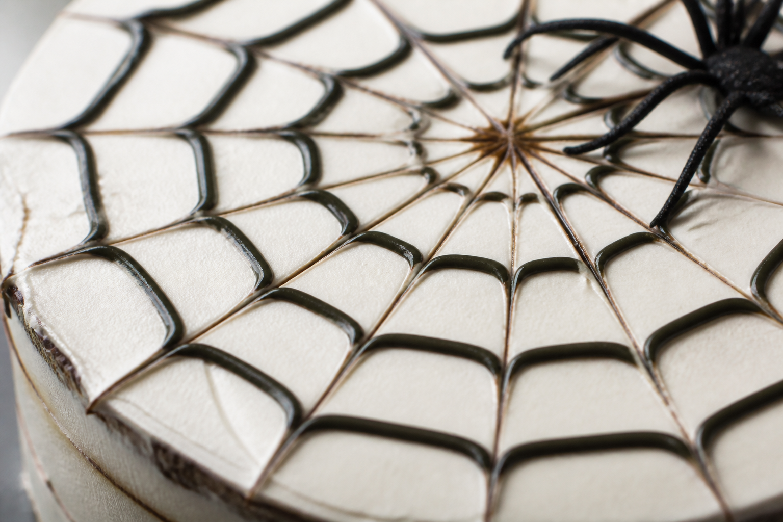 Close-up of buttercream spiderweb lines on a pale frosting sheet cake