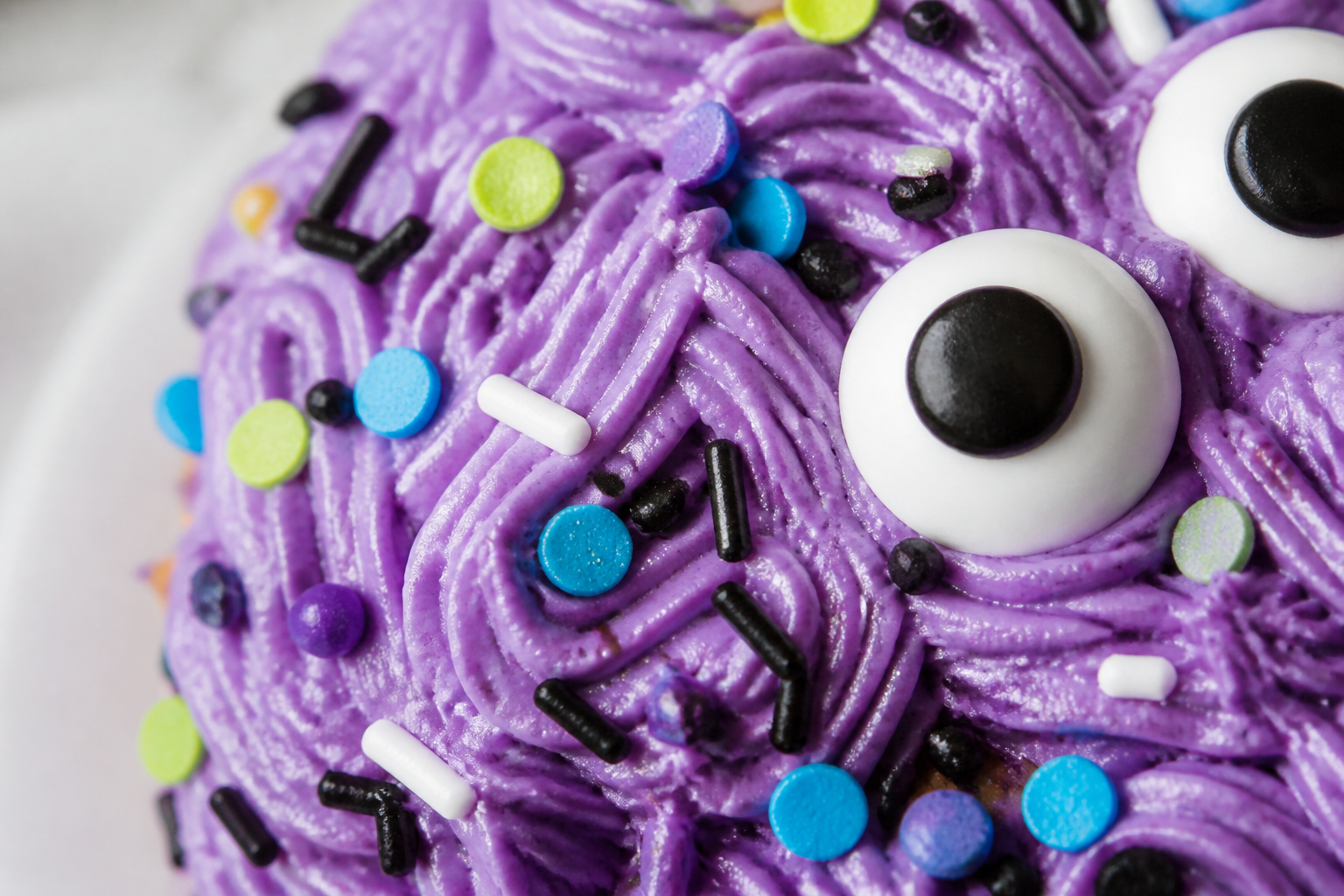 Close-up of purple buttercream and glossy candy monster eyes on the Halloween monster eye cake