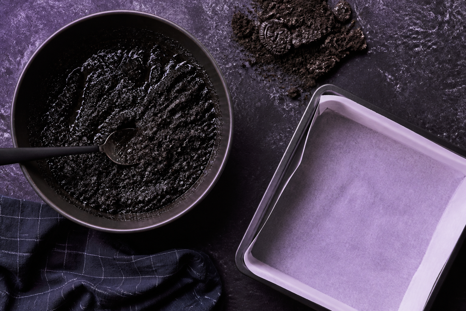 Mixing the black cocoa Oreo crumb crust with melted butter in preparation for pressing