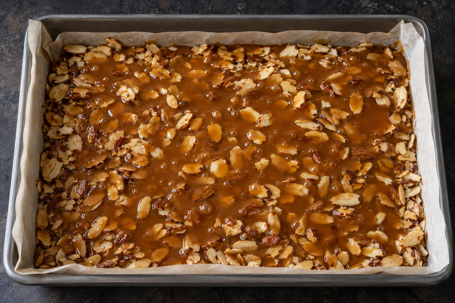 Stage 1: 9×13 pan filled with freshly poured amber butter–almond toffee after cooking to 300°F / 149°C.