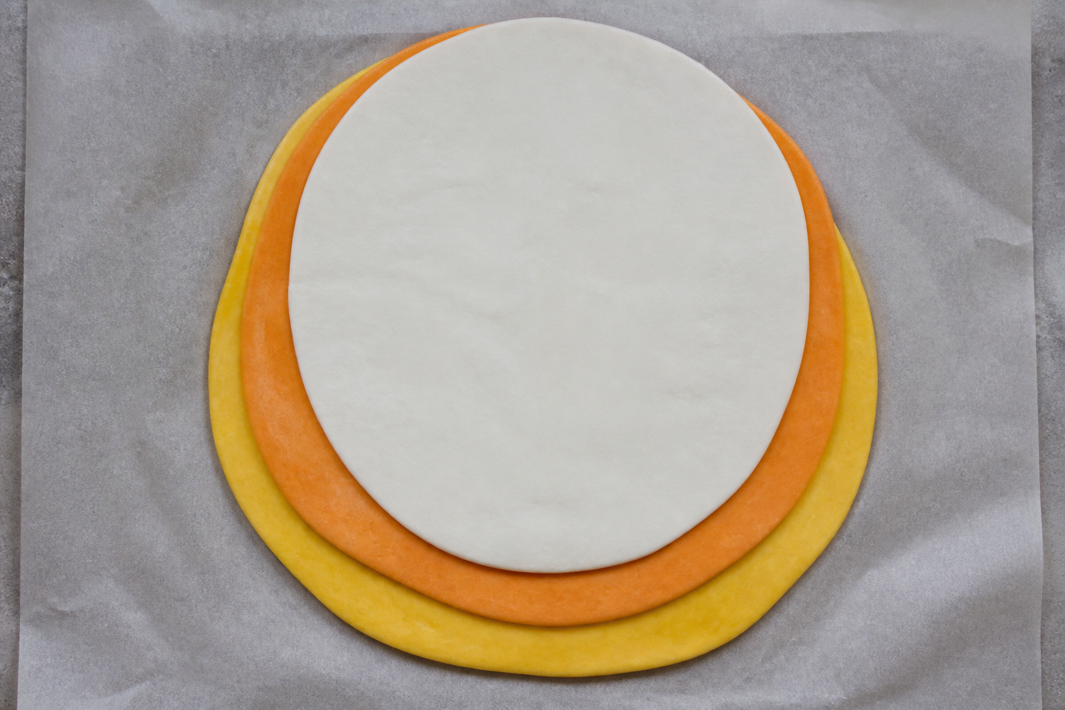 Top-down view of stacked tri-color dough layers ready to chill and slice