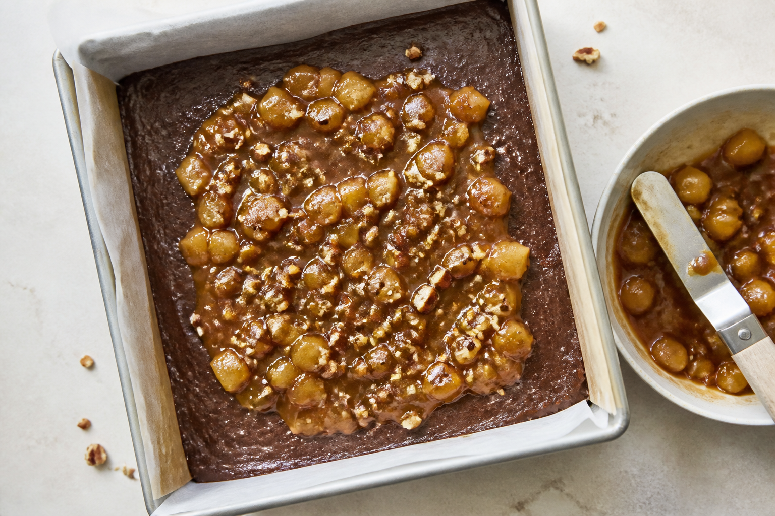 Assembled pan stage with brownie batter spread, pear caramel swirl ready, and toasted nuts on top