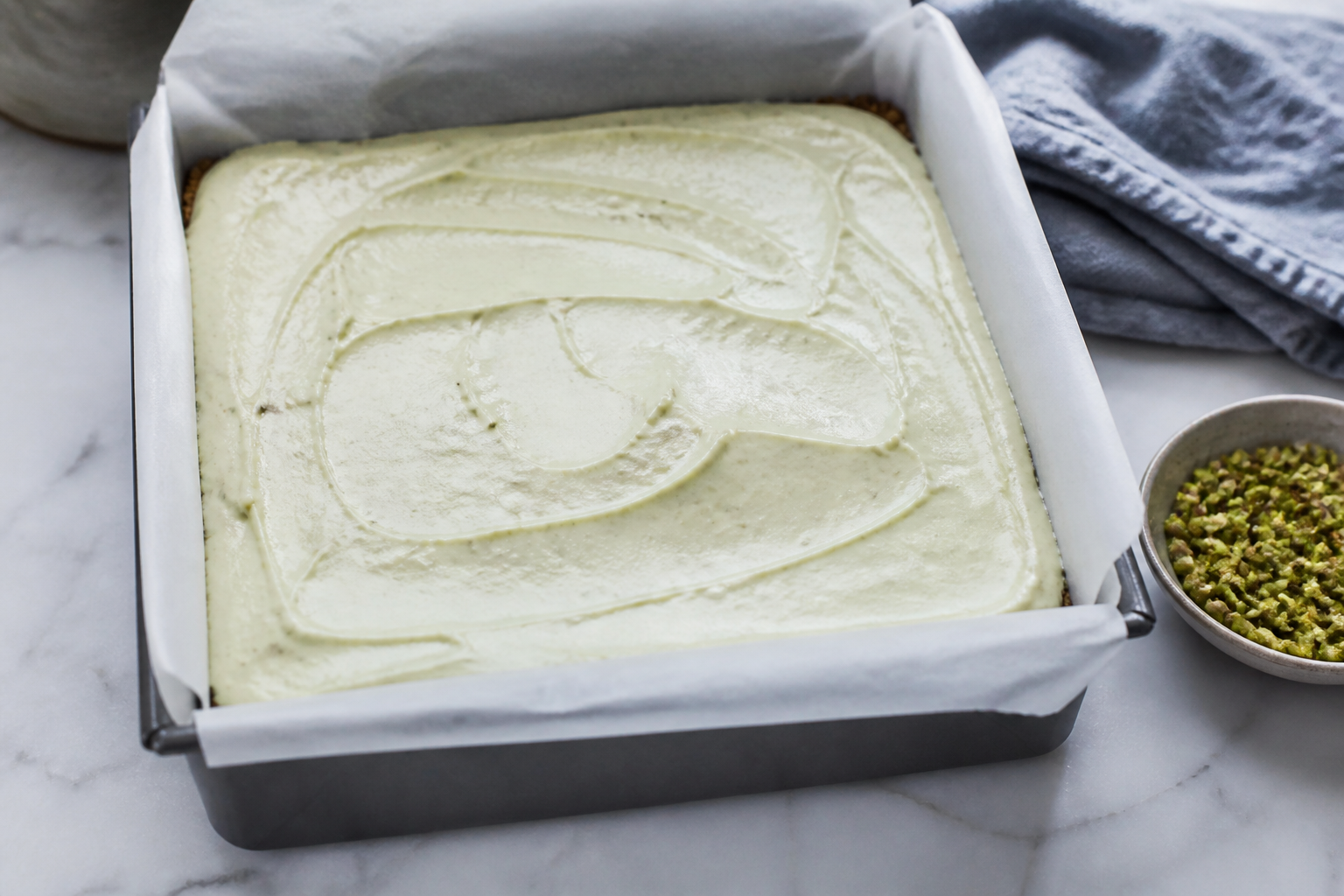 Smooth pistachio cardamom filling spread over the cookie crust in the pan