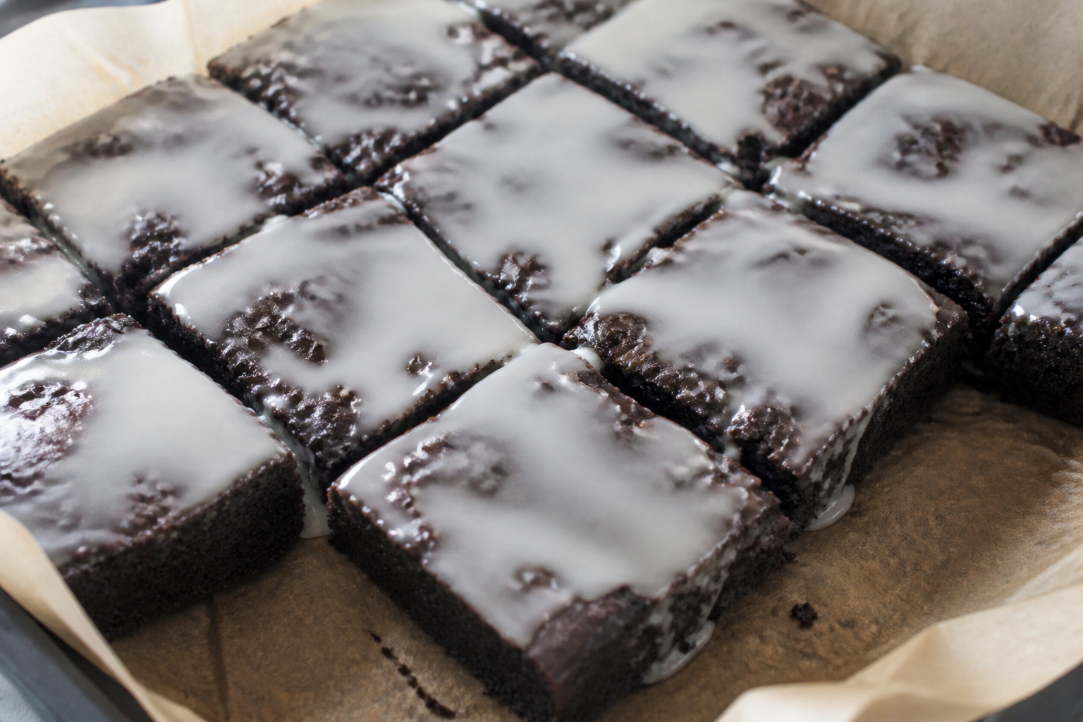 Baked black cocoa brownies cooling then topped with a thin vanilla glaze layer before moon-phase decoration