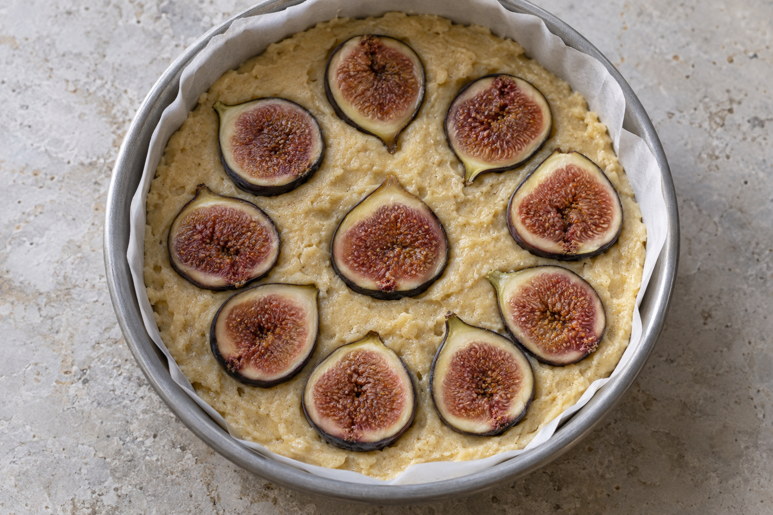 Top-down view of cake pan with figs pressed into the batter before baking