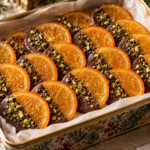 Chocolate covered orange slices with translucent candied citrus and chopped pistachios.