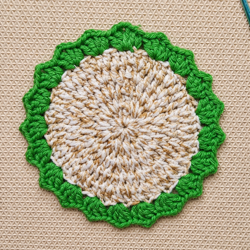 Full green scalloped crochet border completed around the coaster.