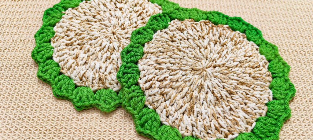 Pair of finished sea grass crochet coasters with ivory centers and green borders.
