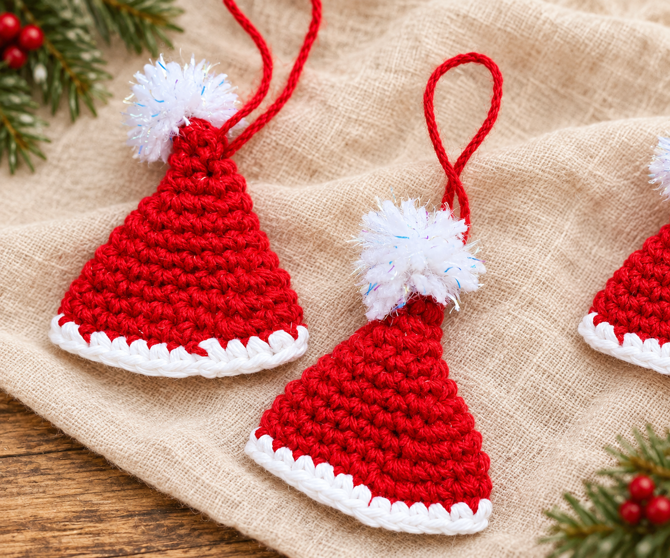 Three finished crochet mini Santa hat ornaments with red single crochet, white brims, pom-poms, and hanging loops.