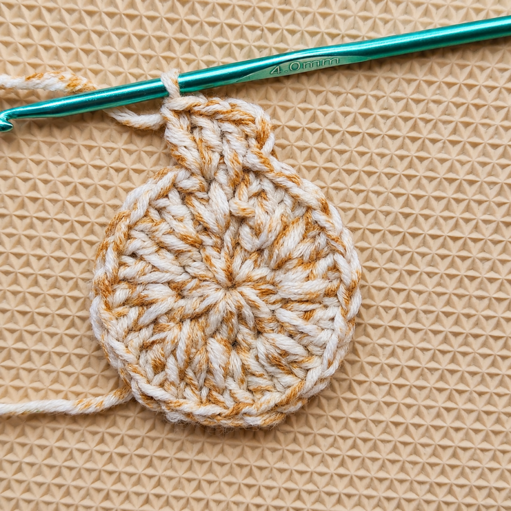 Round 3 nearly complete with the crochet circle lying flat.