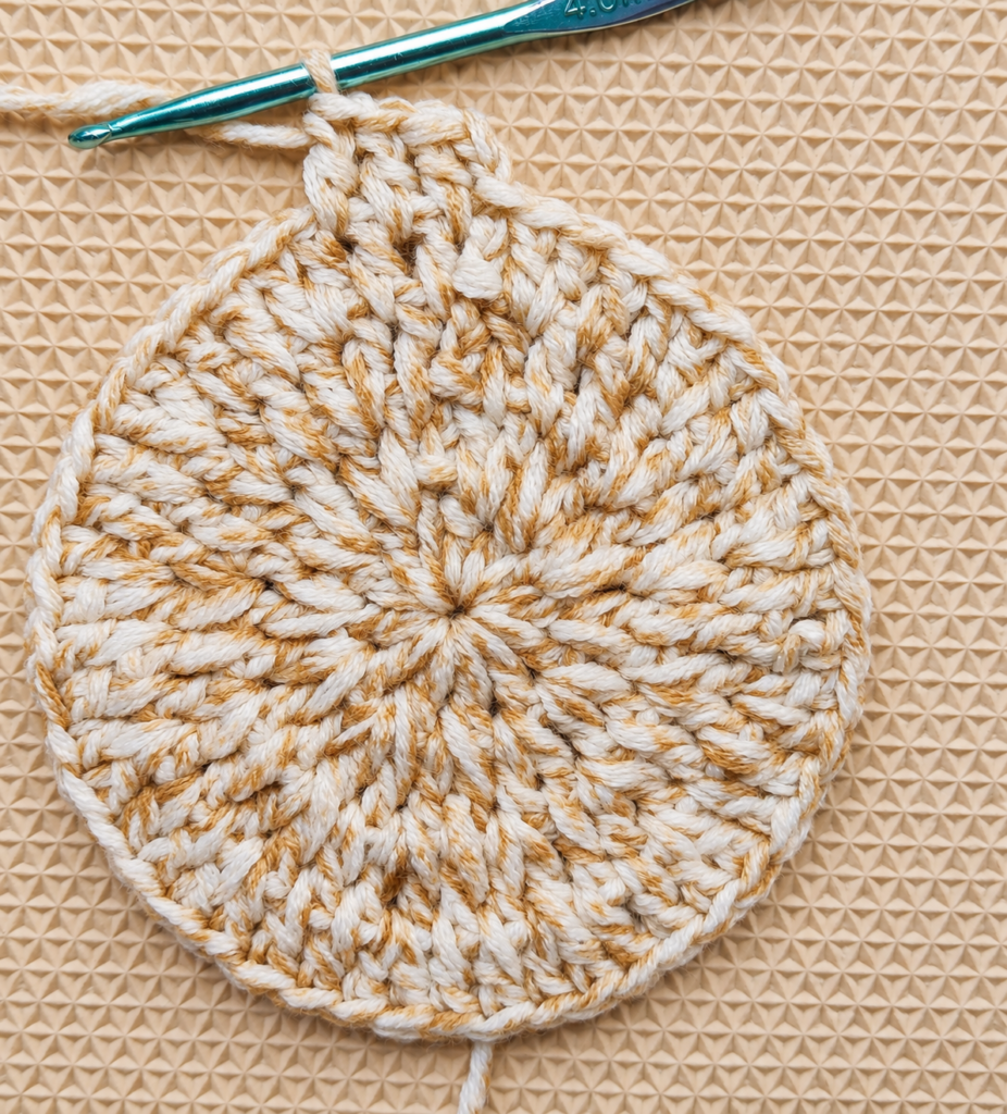 Round 5 beginning on the ivory and tan crochet coaster circle.