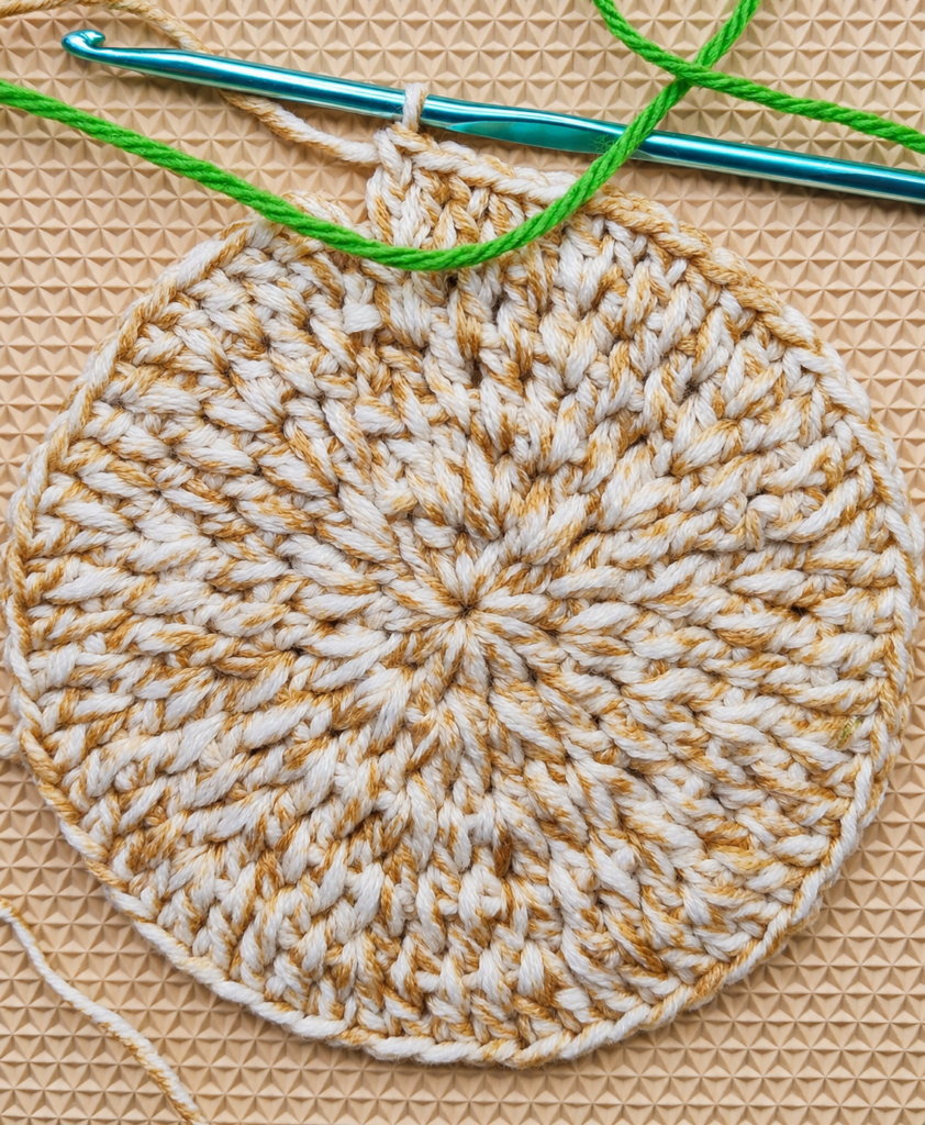 Green cotton yarn laid across the finished fifth round for the color change.
