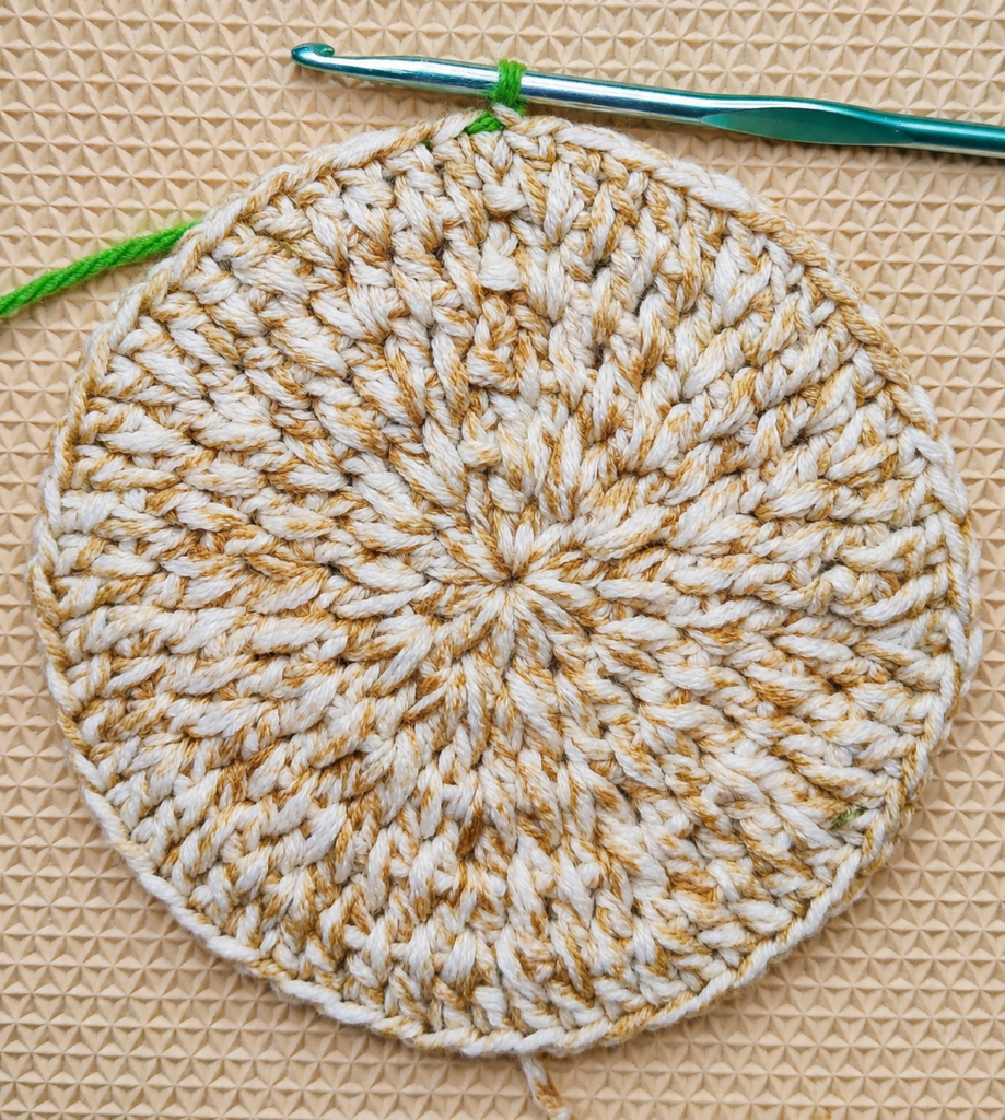 Completed sixty-stitch crochet circle with one green loop on the hook.
