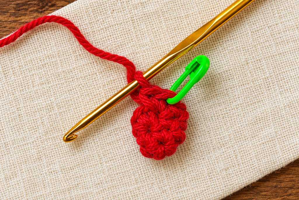 Round 4 of the crochet mini Santa hat ornament showing eight red single crochet stitches.