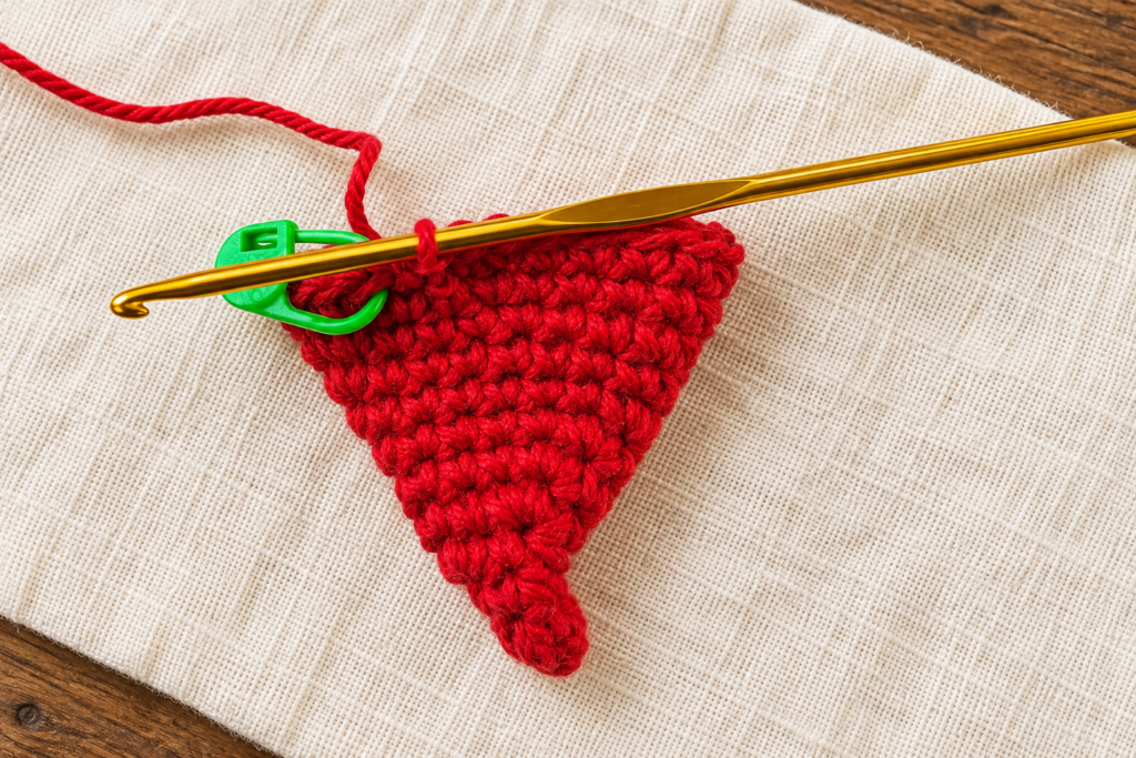 Completed twenty-four-stitch red cone with the active loop and stitch marker in place.