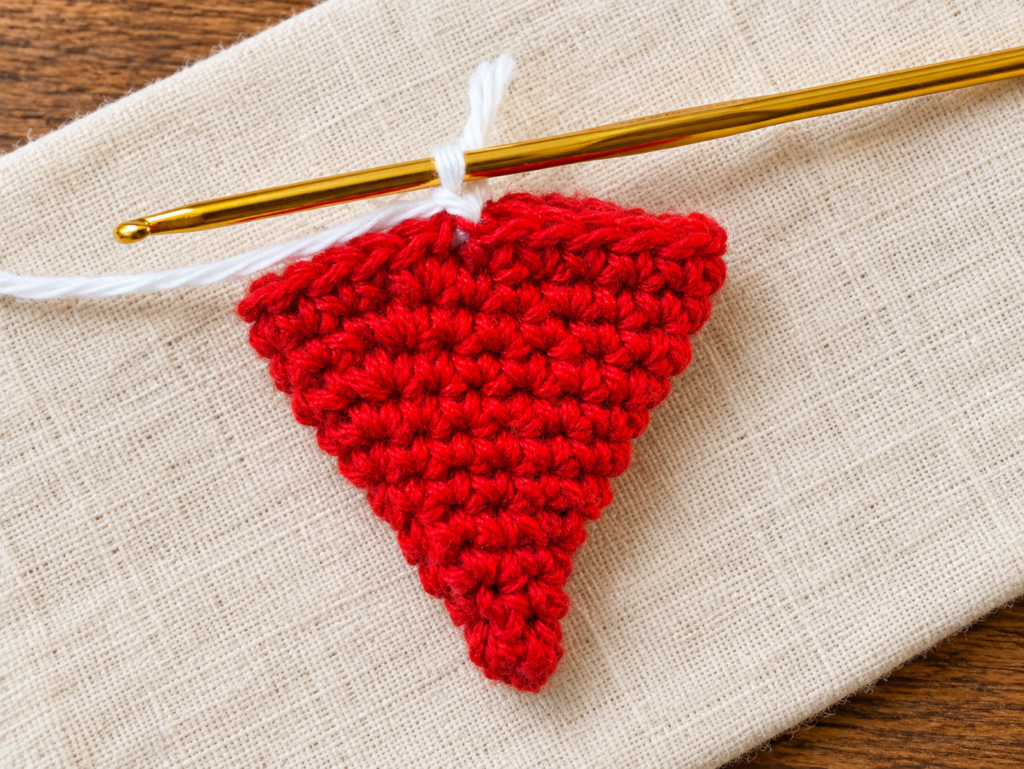 One white loop on the crochet hook after changing color at the red hat edge.