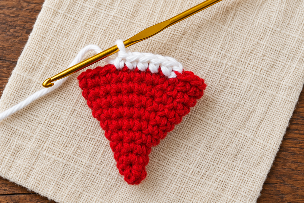 Several white single crochet stitches worked across the red mini Santa hat edge.