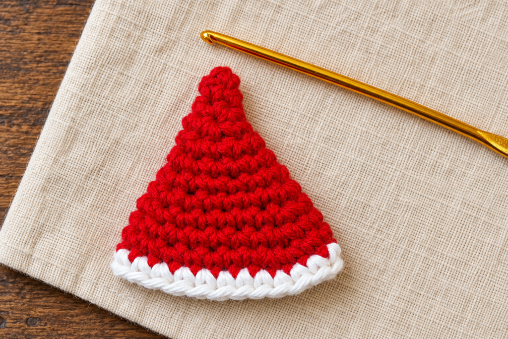Red crochet mini Santa hat cone lying flat with an even white single crochet brim.