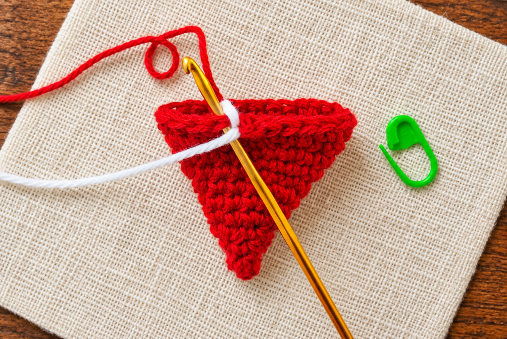 White yarn color change beginning the brim of a crochet mini Santa hat ornament.