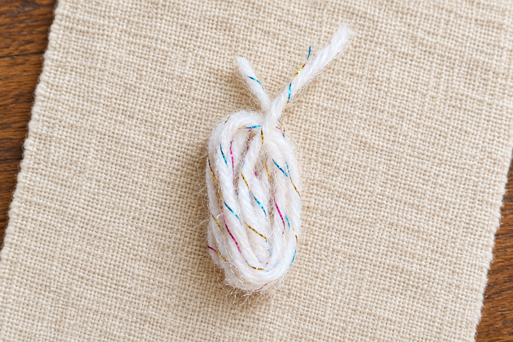 White fluffy novelty yarn loops removed from the fingers before tying the center.